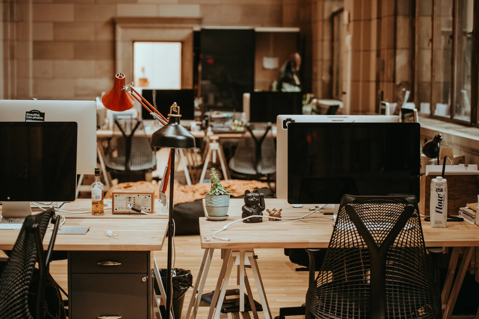 An empty open-plan studio at day's end, desks lit by a single lamp